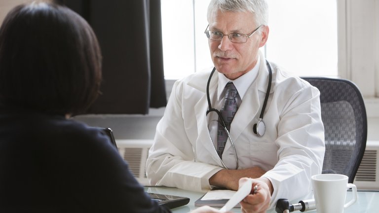 Medico mentre consegna una ricetta ad un paziente